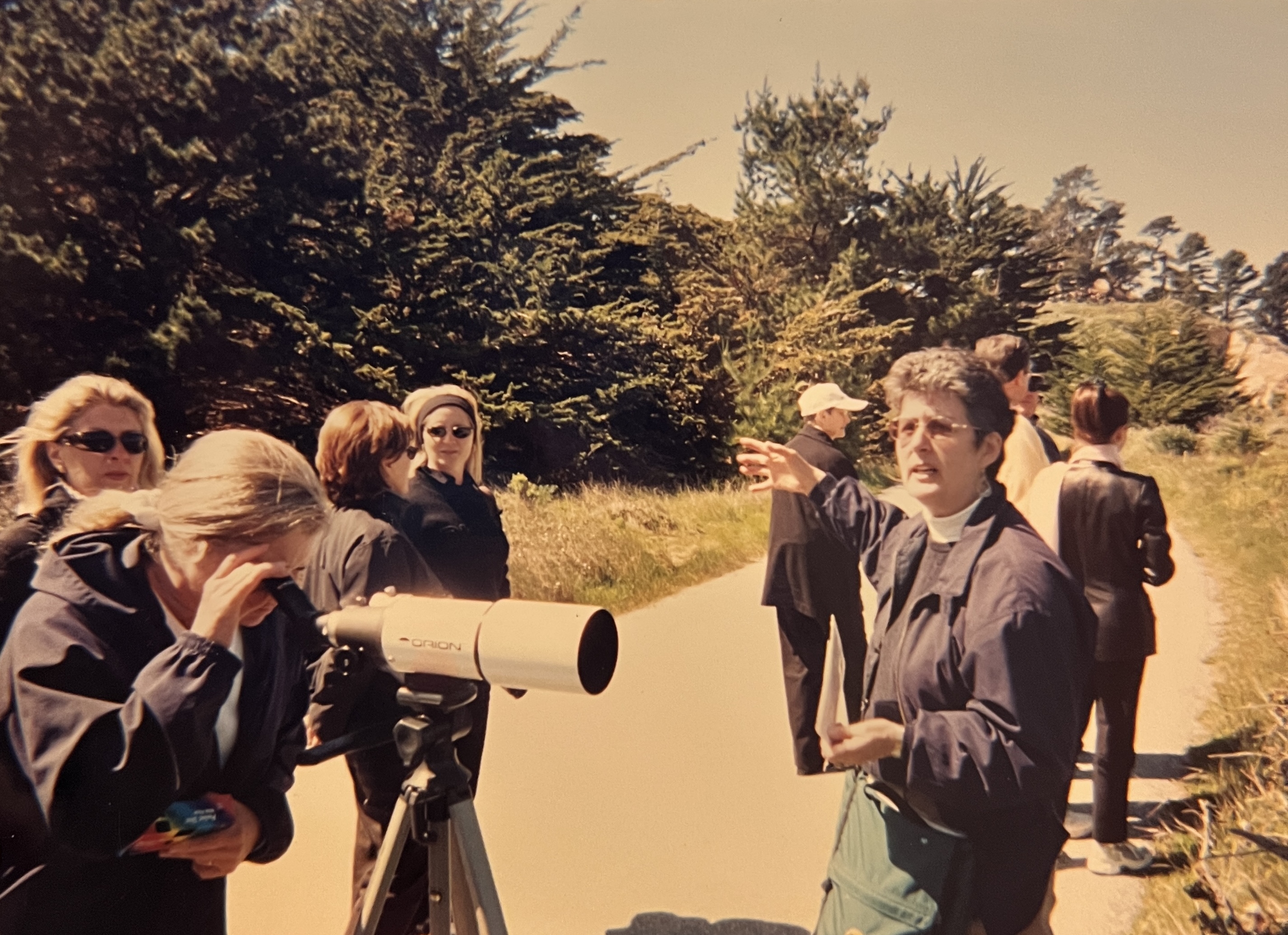 Gael passionately describes the coastal environment to a group of visitors during a walking tour at Point Lobos, using a telescope to offer a closer look at marine life.