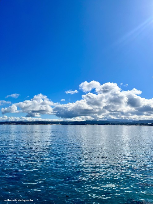 A tranquil view of Monterey Bay with calm blue waters and scattered white clouds reflecting in the sunlight.